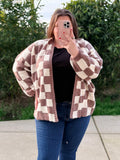 Person wearing a brown and white checkered cardigan outdoors.