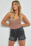 Woman wearing a brown tank top and black shorts against a white background