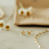 Gold butterfly earrings on a light surface with a blurred background