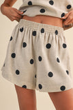 Beige shorts with black polka dots worn by a person on a beige background