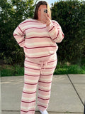 Person wearing a pink and red striped outfit taking a mirror selfie outdoors.