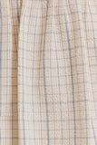Close-up of a cream-colored fabric with a fine blue and gray windowpane plaid pattern.