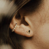 Close-up of an ear with gold butterfly earrings.