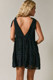 Woman wearing a black polka dot dress with a plain background