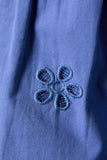 Close-up of a blue fabric with a floral embroidery design.