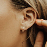 Close-up of an ear wearing gold earrings with a blurred background