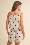 Woman wearing a polka dot sleeveless top and shorts on a beige background