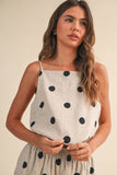 Woman wearing a polka dot dress against a beige background