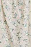Floral patterned fabric with small blue flowers and green leaves on a beige background