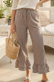 Person wearing checkered pants with ruffled bottom hem, holding a straw bag outdoors.