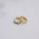 Two gold hoop earrings on a light gray background