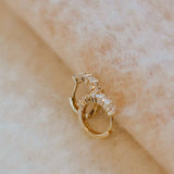 Gold earring with clear stones on a beige fabric background