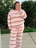 Person wearing a pink and white striped outfit taking a mirror selfie outdoors.