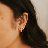 Close-up of an ear wearing a diamond earring with a blurred background