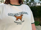 Person wearing a t-shirt with 'Golden Dreams Retriever Club' design.