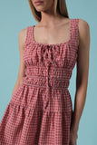 Woman wearing a red and white checkered dress against a blue background