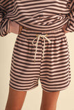 Person wearing a striped outfit with shorts and a top on a beige background
