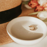 Two rings on a white ceramic dish with a blurred floral background