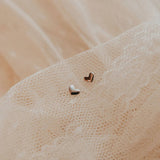 Heart-shaped earrings on a textured beige fabric background