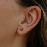 Close-up of an ear wearing a gold bow-shaped earring.