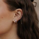 Close-up of an ear with multiple earrings against a blurred background