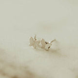 Butterfly-shaped silver earrings on a beige background