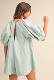 Woman wearing a light green dress with balloon sleeves on a beige background